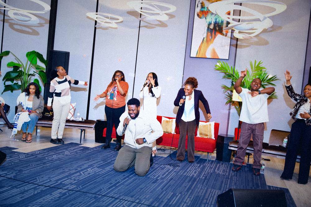 Worship team leading while one person kneels in prayer