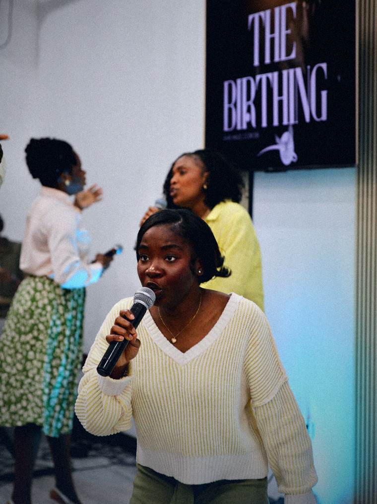 Worship leader singing beneath a screen reading The Birthing