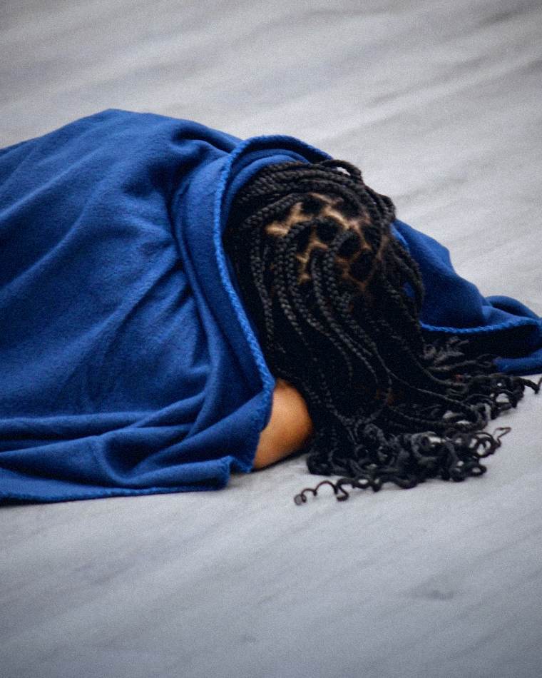 A believer resting on the floor under a blue blanket