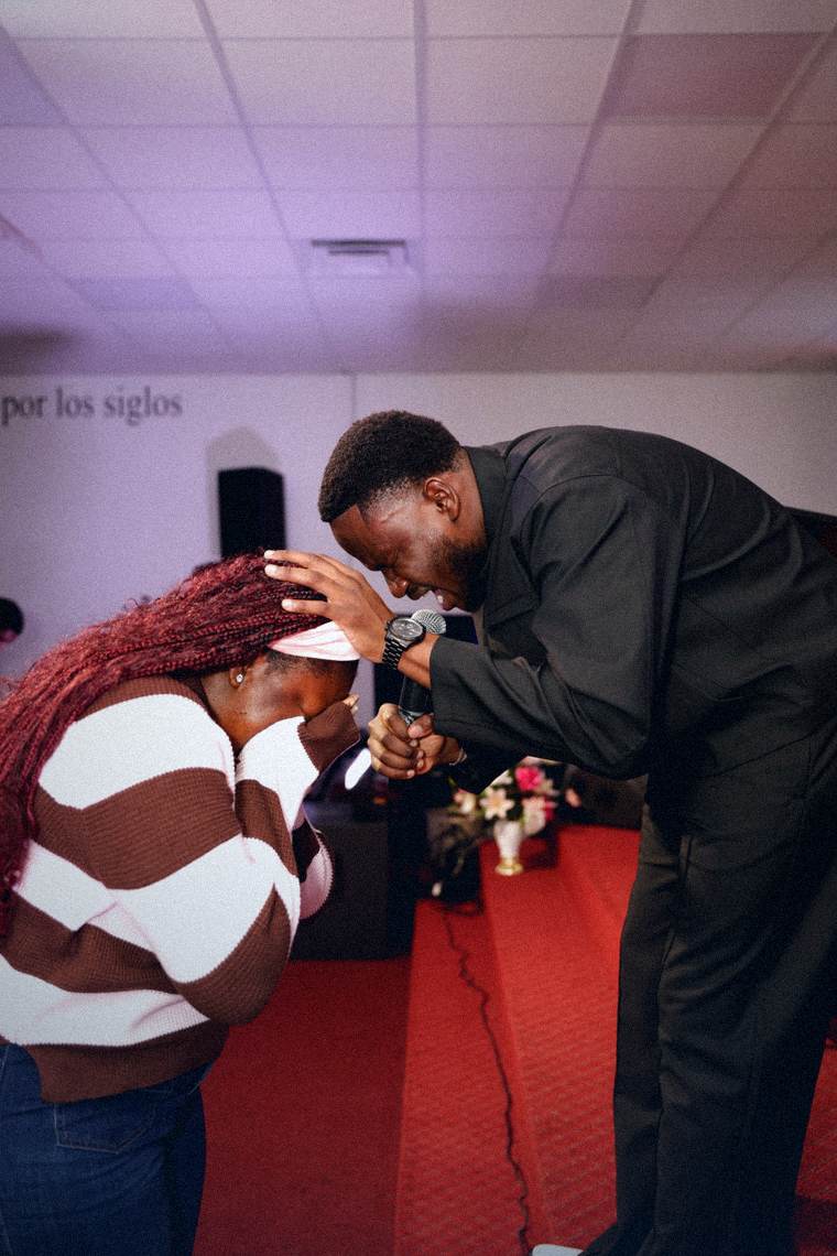 Minister praying over a woman who is weeping