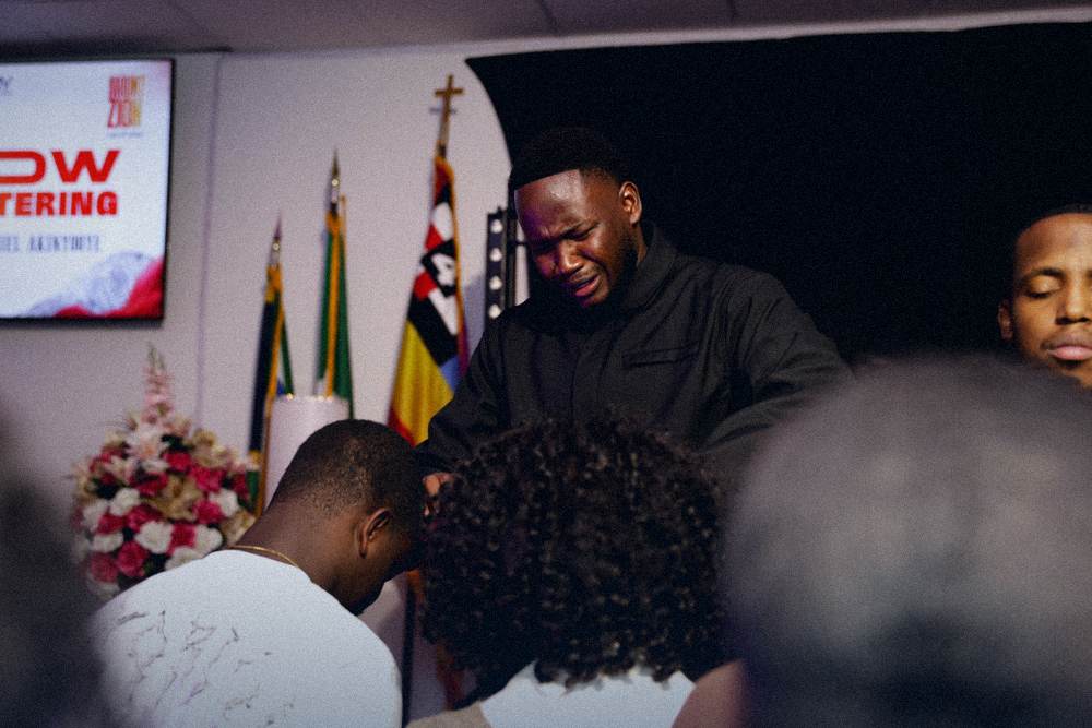Minister weeping while praying for a man at the altar